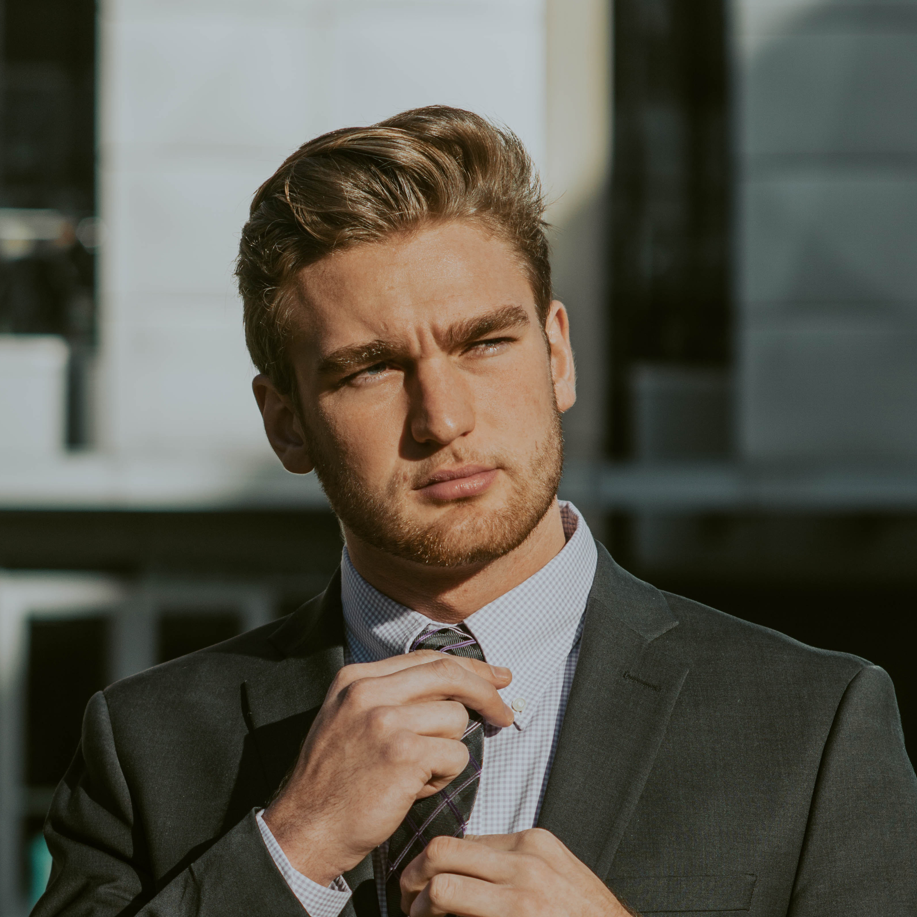 Man straightening tie with questioning look