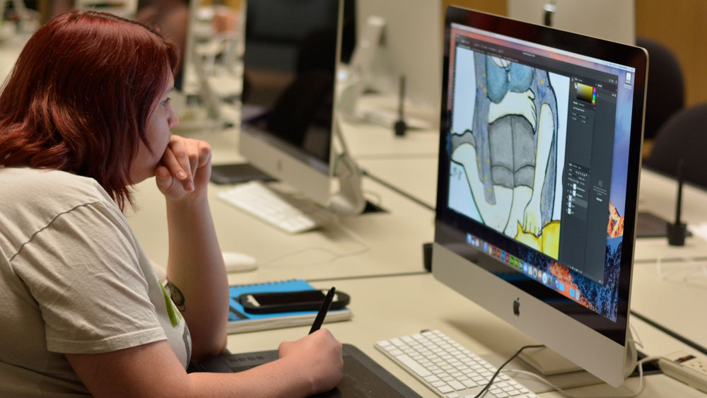 female student creating a drawing on an iMac and using a electronic drawing tablet