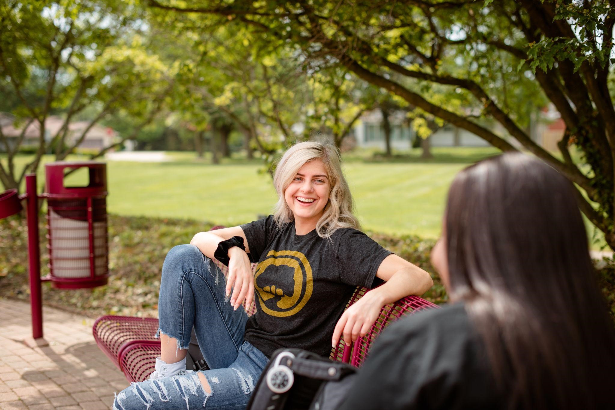Students taking a break and conversing on a bench on main campus