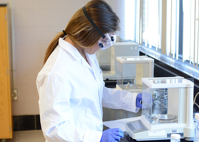 Female student in safety gear using centerfuge