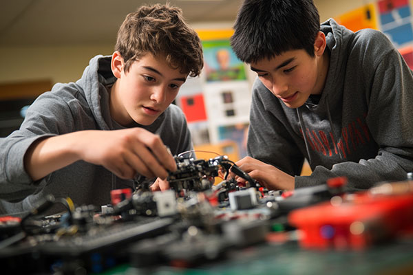 Two young boys working on elecronics or drones