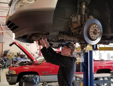 student working on automobile on lift